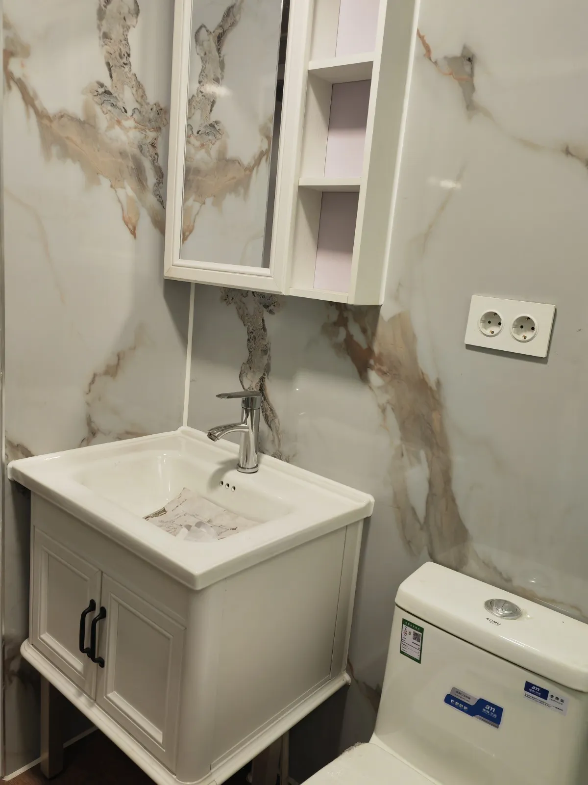 Mueble de lavabo crema con espejo sobre fondo de mármol calacatta en la Canet