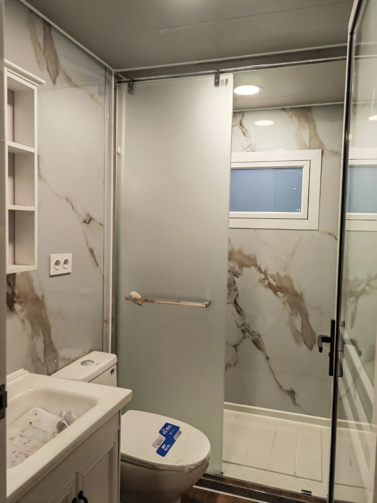 Baño de la Canet revestido en mármol calacatta con ducha y mampara de vidrio