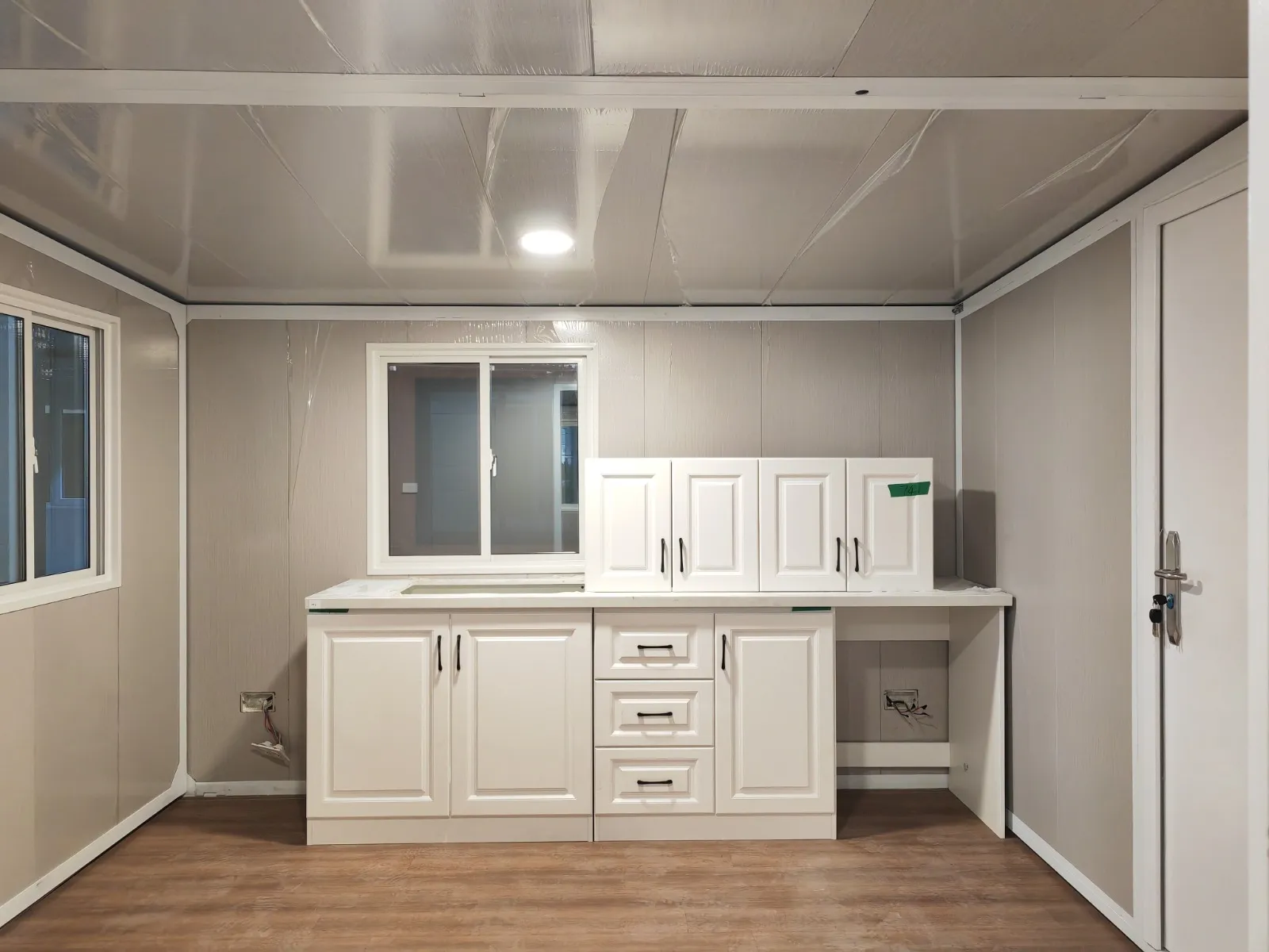 Cocina de la Canet con muebles blancos y fregadero de acero inoxidable bajo la ventana