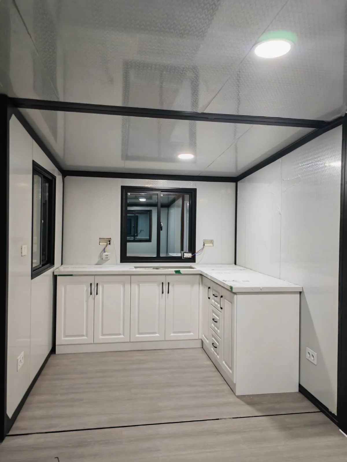 Cocina en L de la Morvedre con muebles blancos, encimera de efecto mármol y fregadero bajo la ventana