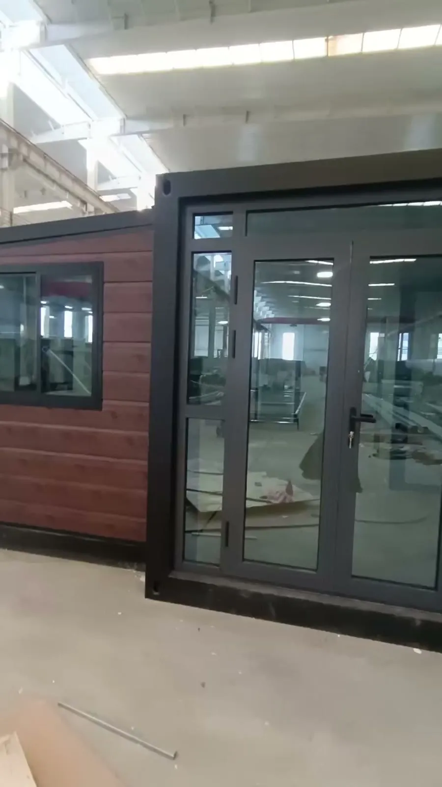 Casa modular plegada con efecto madera y carpintería en grafito